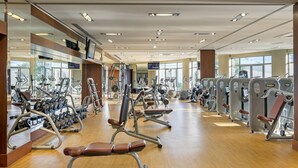 A gym with various exercise machines, large windows, and a wooden floor. - Titanic Business Kartal (Istanbul)