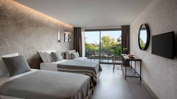 A hotel room with two beds, a TV, a balcony with a table and chairs, and a view of the outdoors.