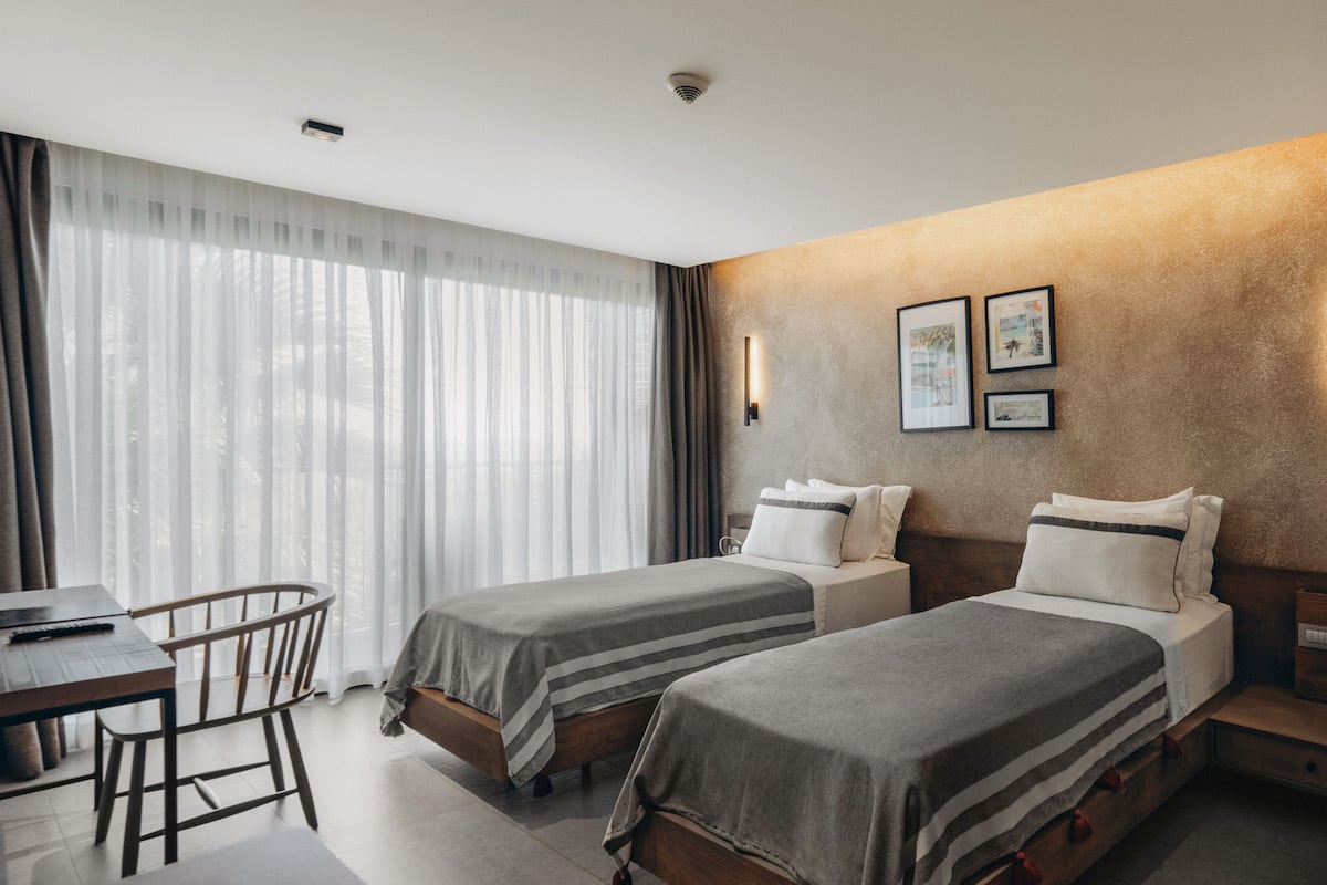 A hotel room with two beds, a desk, and a chair.