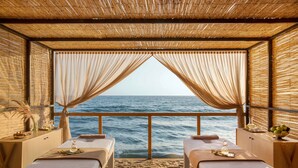 Una habitación con dos camillas de masaje, vista al mar y techo de bambú.