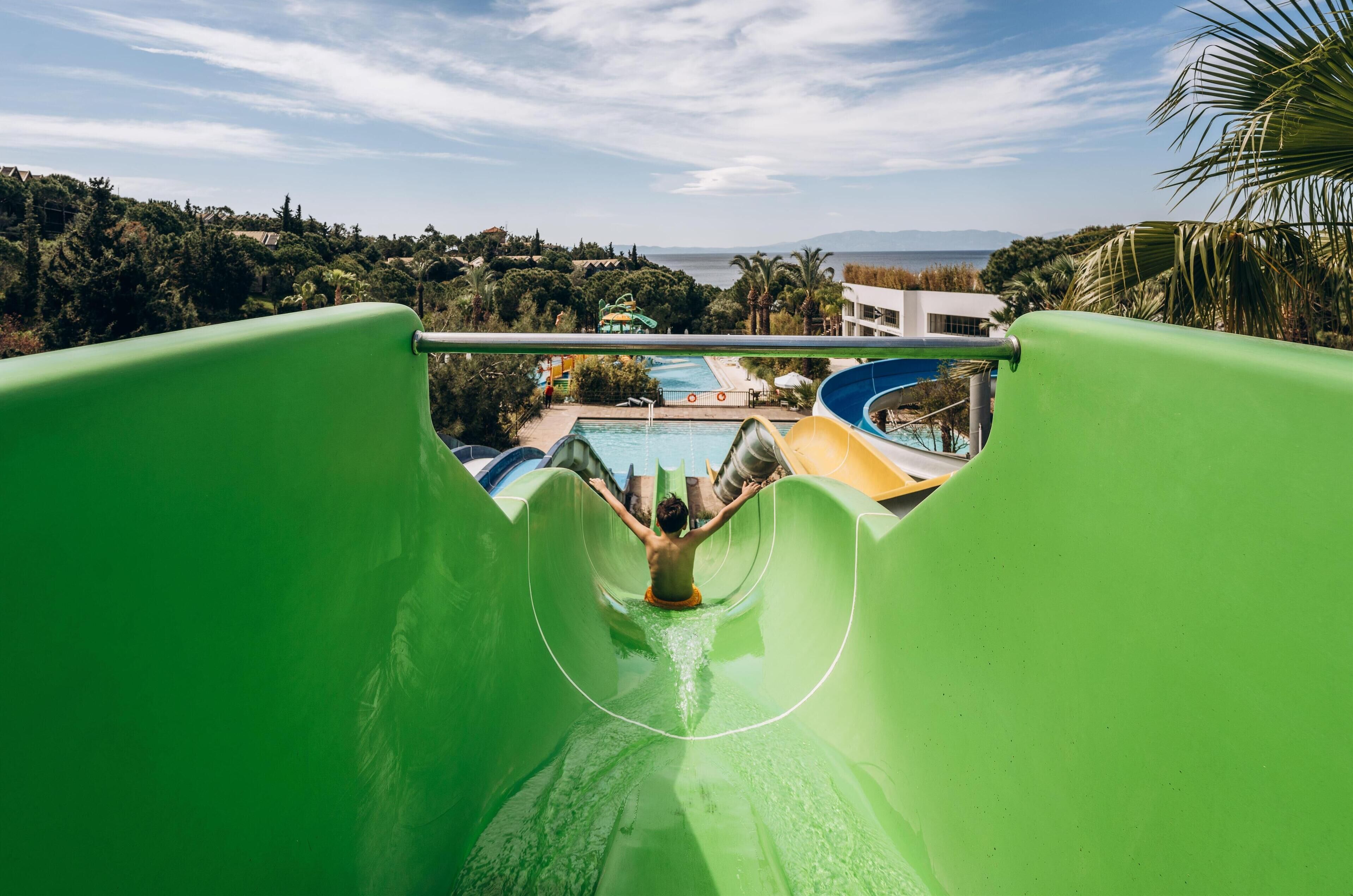 Um tobogã em um resort, com vista para uma piscina e um edifício ao fundo.
