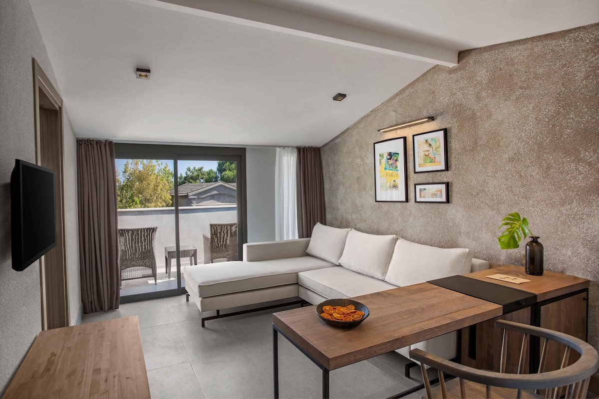 A modern living room with a sofa, a dining table, and a TV.