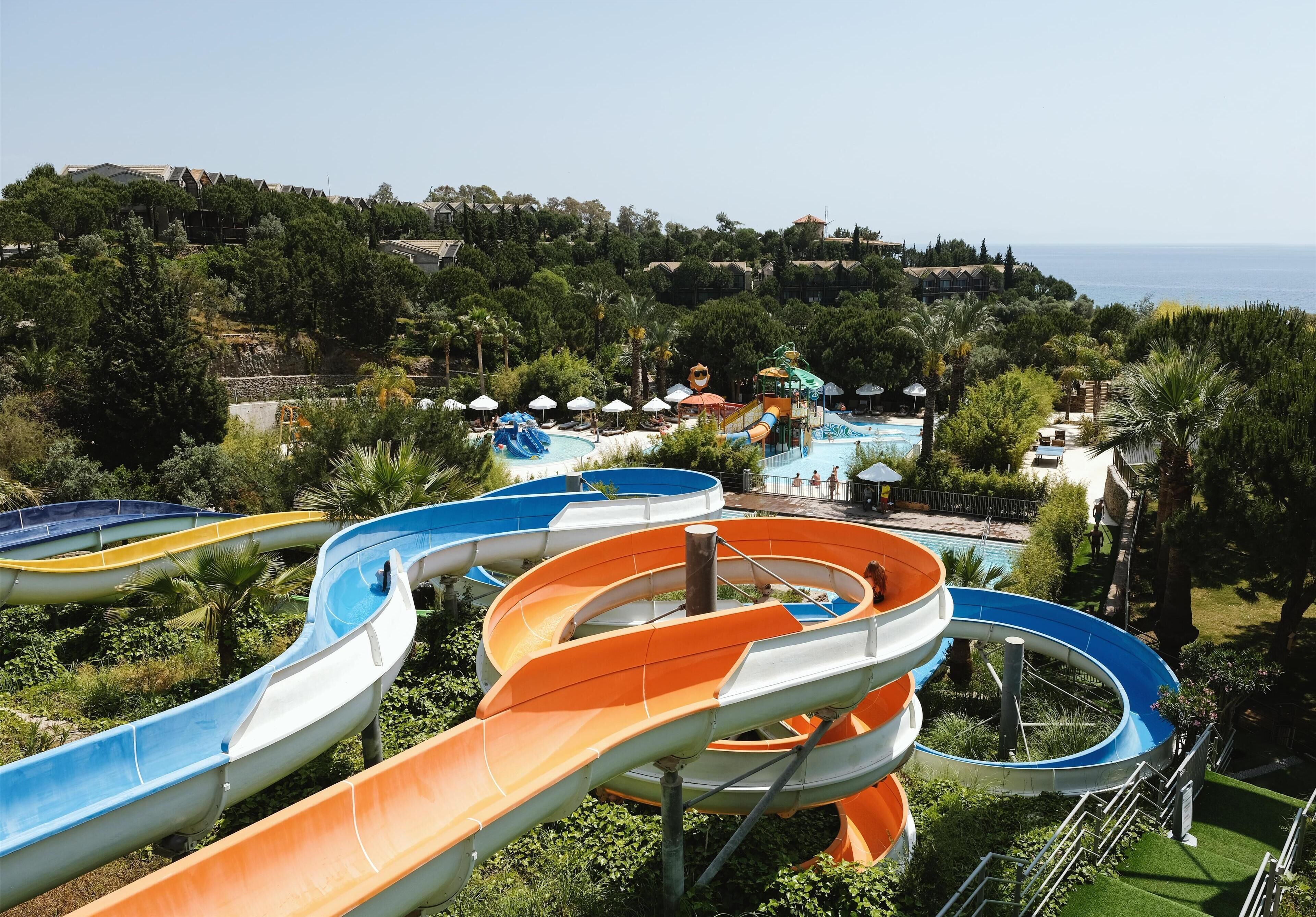 A water park with multiple slides and a pool area surrounded by greenery and buildings.