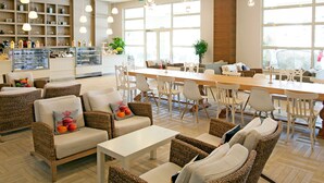 A spacious lounge area with wicker furniture, a long dining table, and hanging pendant lights. - Paloma Oceana - All inclusive (Manavgat)