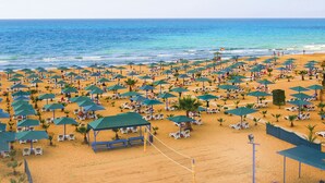 A beach with numerous umbrellas and sun loungers, a volleyball net, and a clear view of the ocean. - Paloma Oceana - All inclusive (Manavgat)
