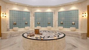 A luxurious bathroom with a central circular marble floor, multiple sinks, and decorative wall tiles. - Paloma Oceana - All inclusive (Manavgat)