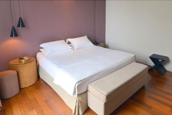 Un dormitorio con cama, mesitas de noche y un banco.