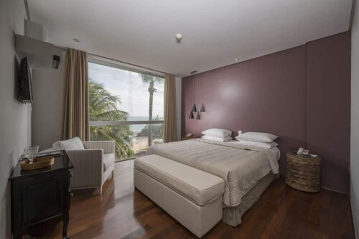 A modern bedroom with a large window, a bed, a bedside table, and a chair.