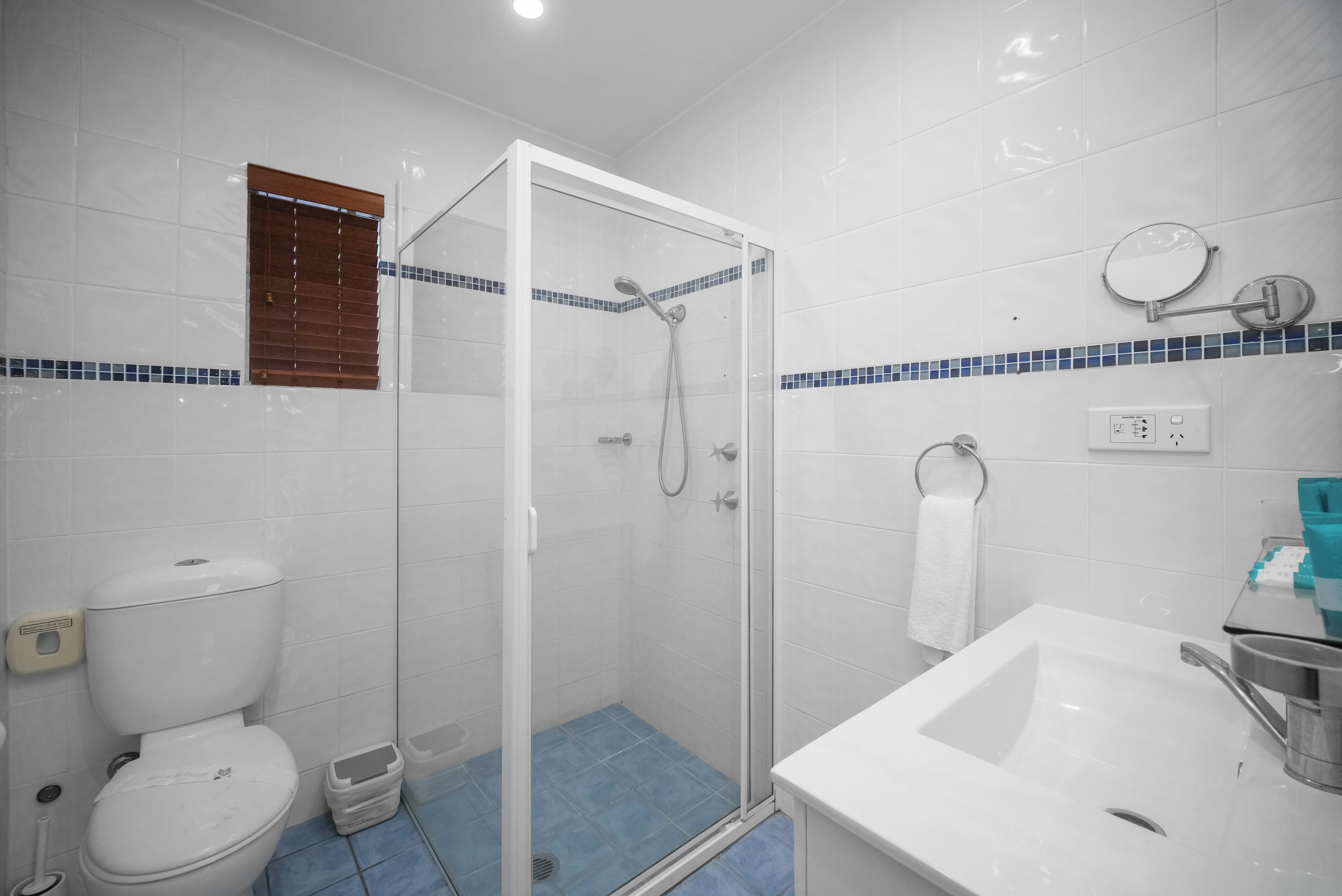 Une salle de bain avec une douche à parois de verre, un lavabo blanc et des toilettes.