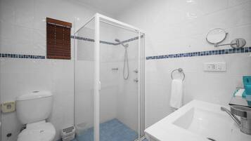 Une salle de bain avec une douche à parois de verre, un lavabo blanc et des toilettes.