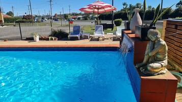 Una piscina al aire libre, sillones reclinables de piscina