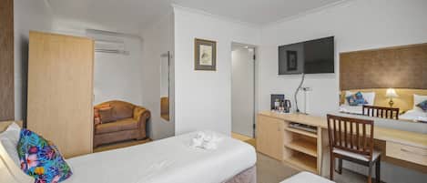 A hotel room with two beds, a desk, a chair, a TV, and a wardrobe.