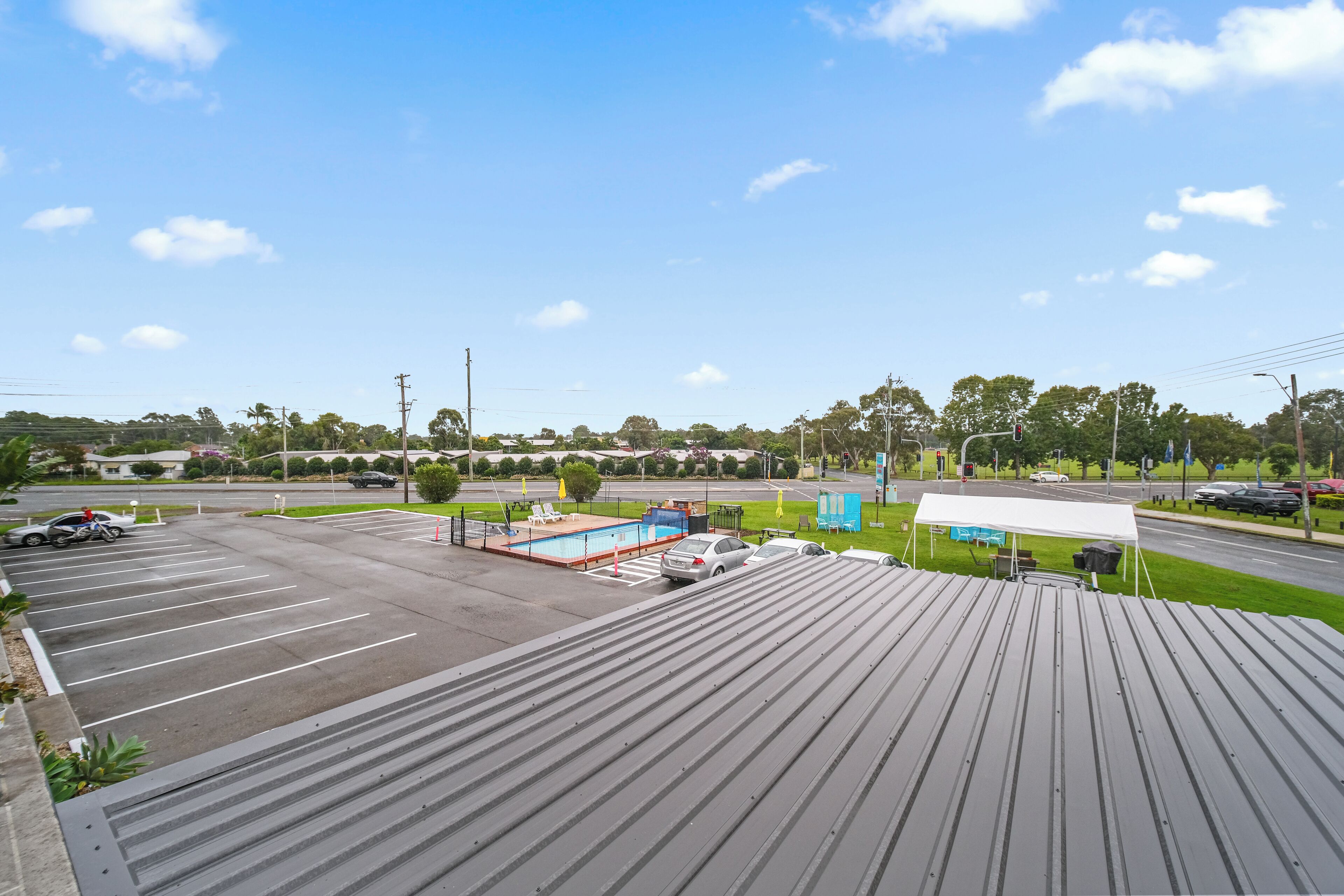 A parking lot with a swimming pool, a covered area, and a road intersection.