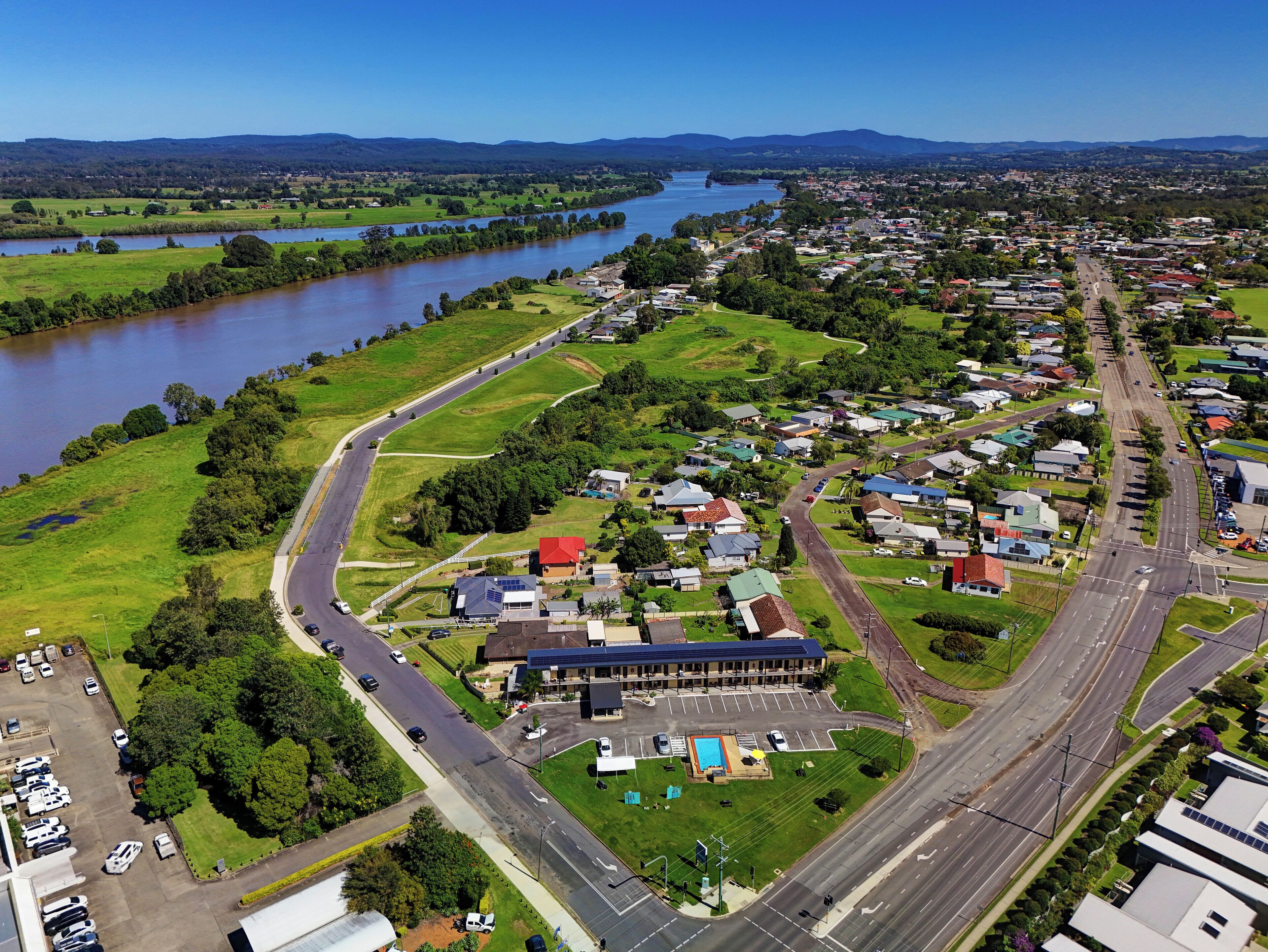 Vista aérea de una zona residencial con un río, carreteras y un edificio grande con piscina.
