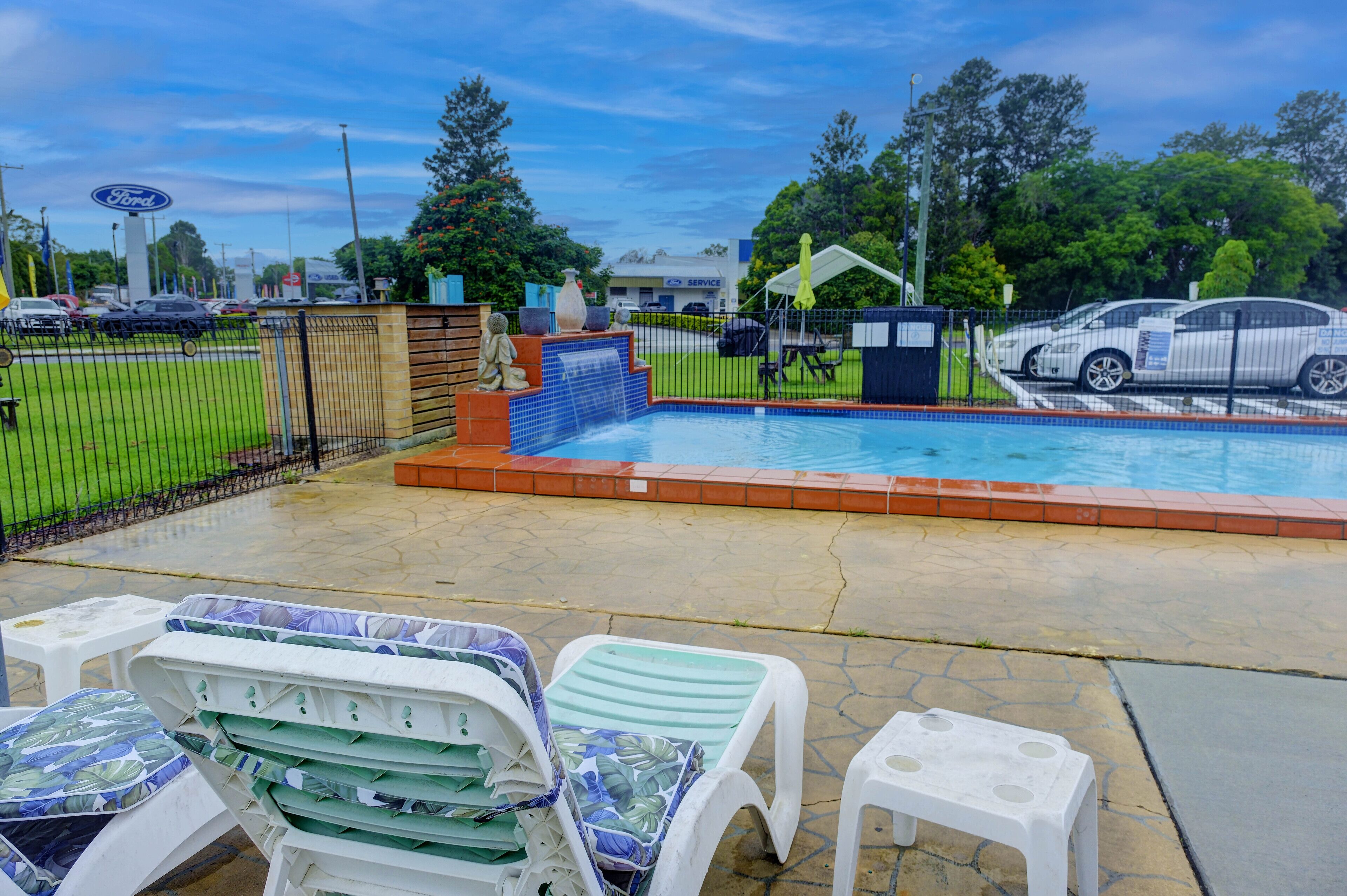 A swimming pool area with lounge chairs and a fence.