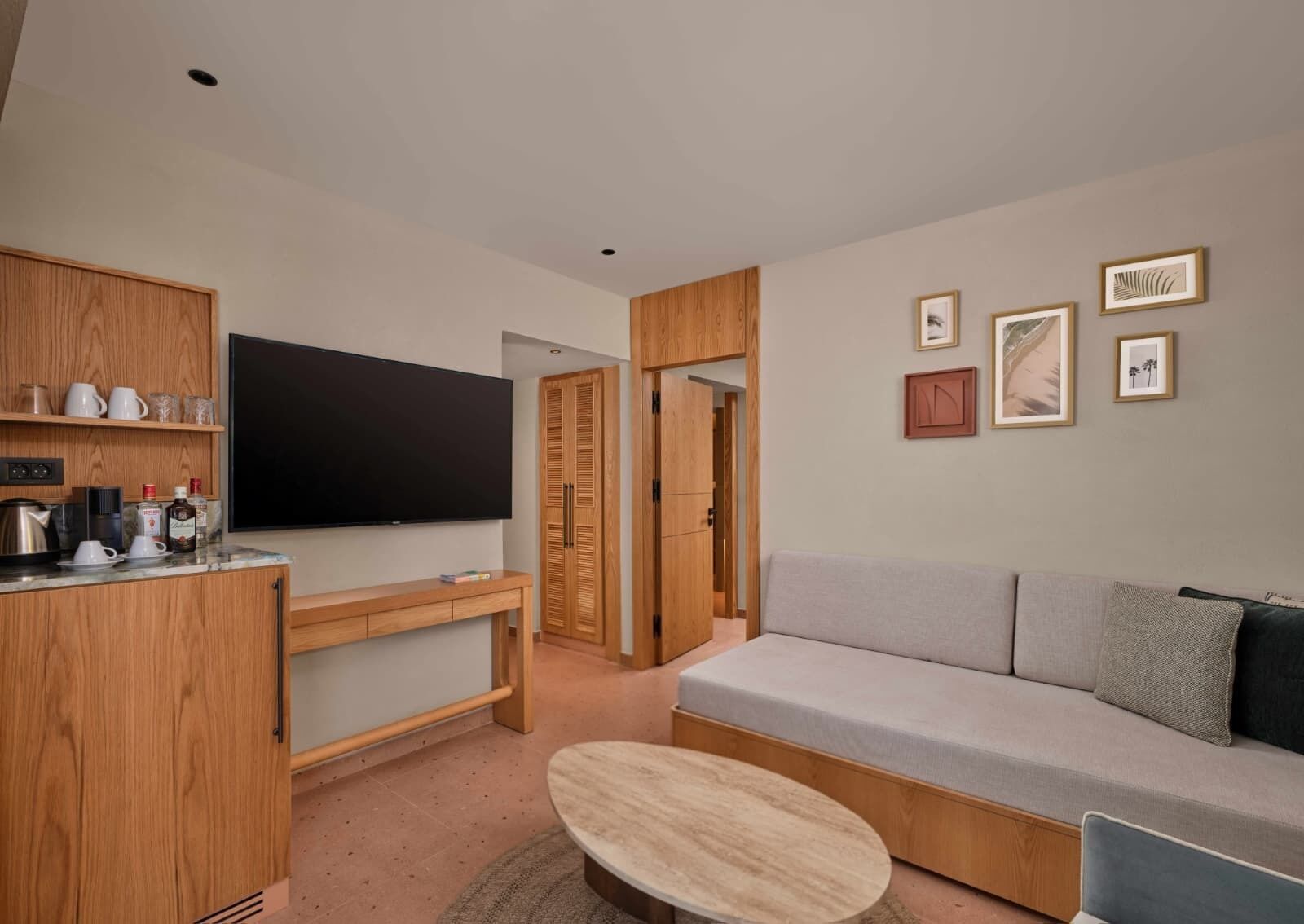Een moderne woonkamer met een grijze bank, houten kasten, een flatscreen televisie en een salontafel.