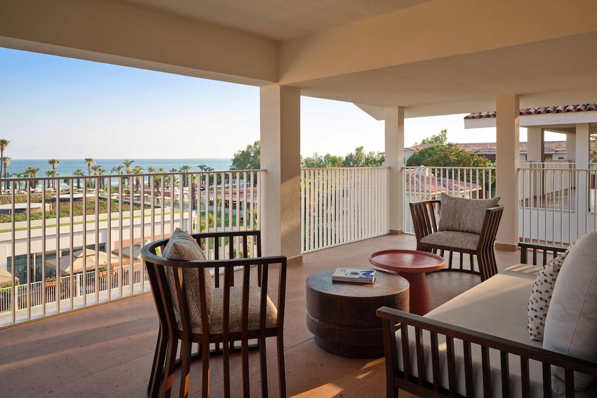 Een balkon met uitzicht op zee, voorzien van stoelen en een tafel.