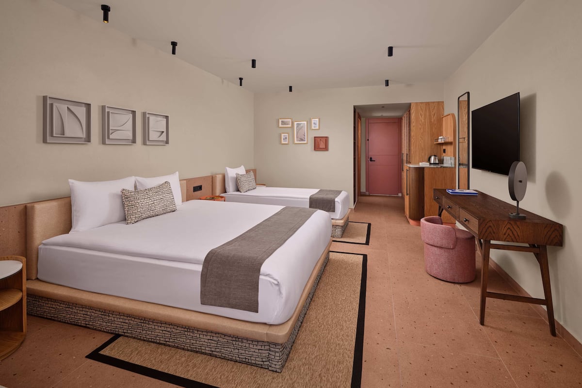 Een hotelkamer met twee bedden, een bureau, een spiegel en een televisie.