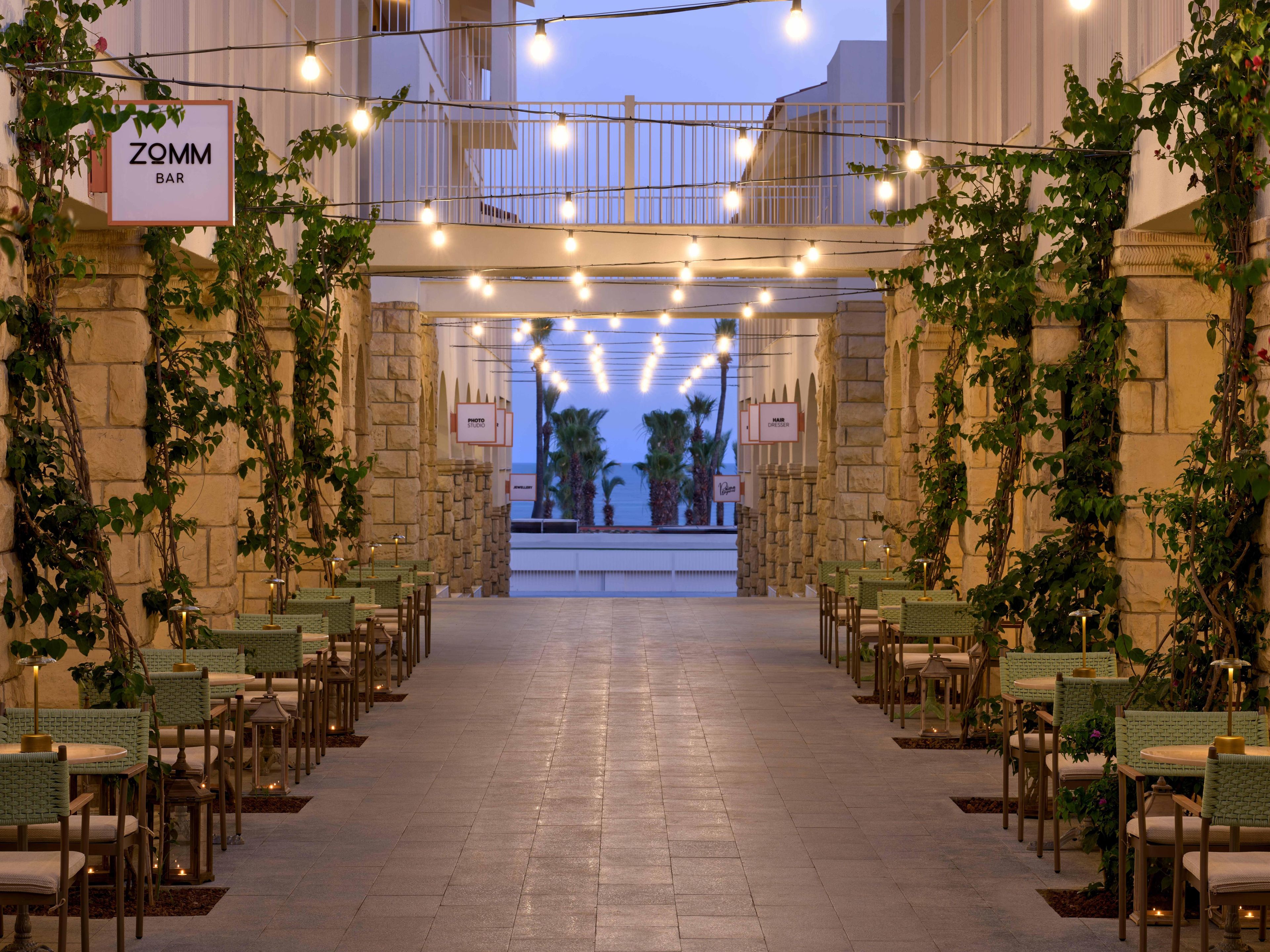 A bar named ZOMM BAR with outdoor seating and string lights.