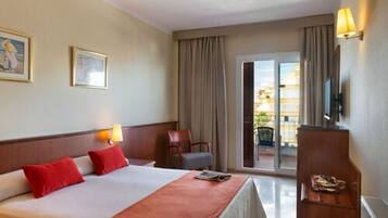 Habitación de hotel con cama, una silla, escritorio, televisión y vistas al exterior.
