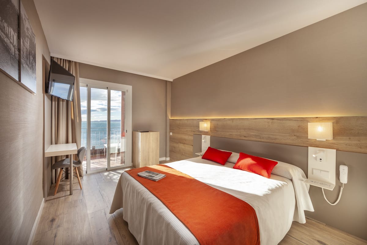 A modern hotel room with a large bed, a desk, and a view of the outdoors.