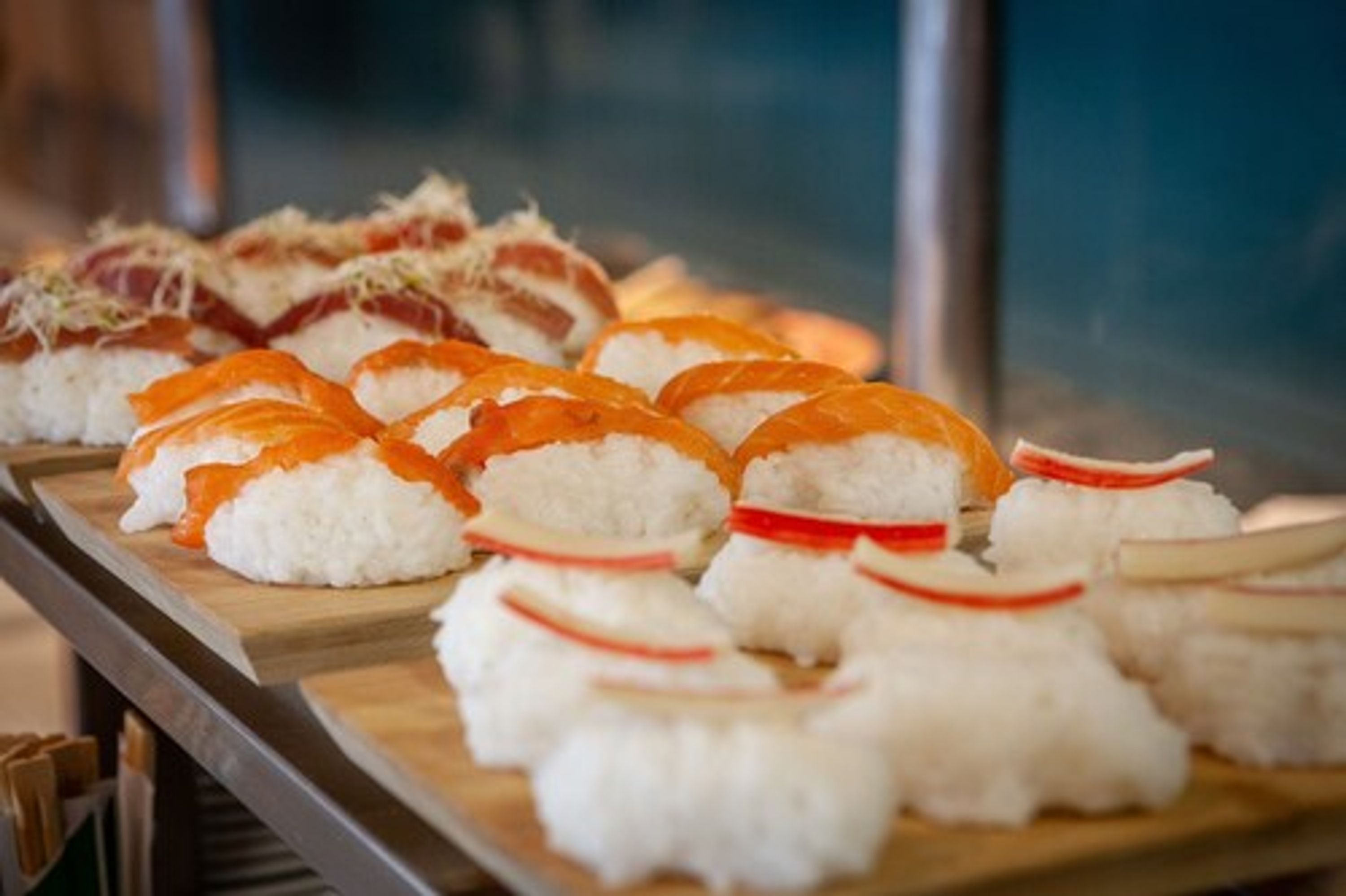 Una bandeja de sushi con diferentes tipos de sushi, incluyendo rollos de salmón y atún, dispuesta sobre una tabla de madera.