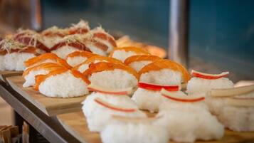 A sushi platter with various types of sushi, including salmon and tuna rolls, arranged on a wooden board.