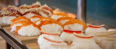 Un plateau de sushis comprenant différents types de sushis, notamment des rouleaux au saumon et au thon, disposés sur une planche en bois.