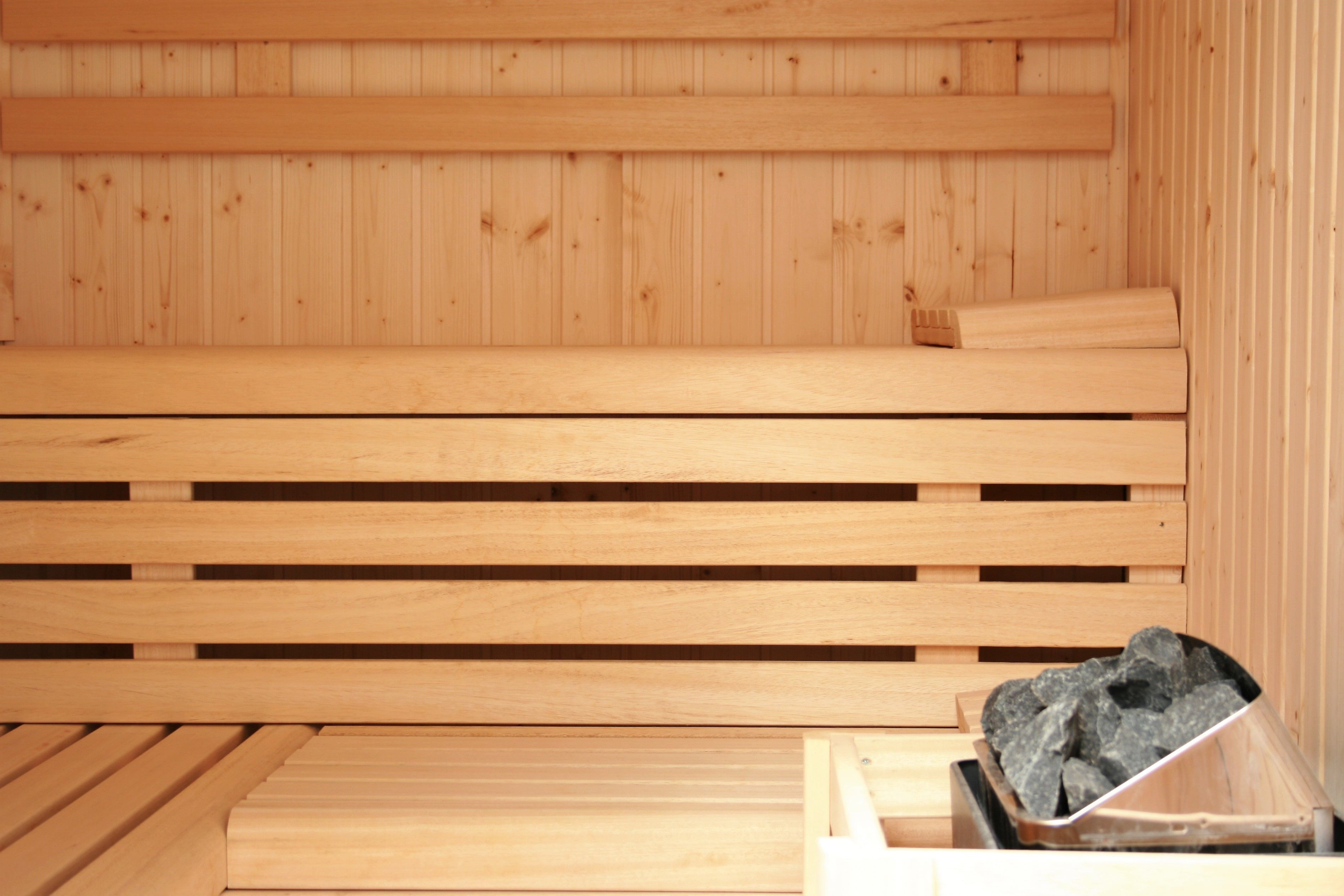 Un sauna en bois, doté de bancs et d’un récipient rempli de pierres.