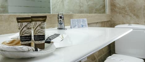 A bathroom with a white sink, two bottles of bath gel and shampoo, a razor, and a tissue box.