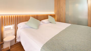 A modern hotel room with a large bed, a bedside table, and a wall-mounted light fixture.