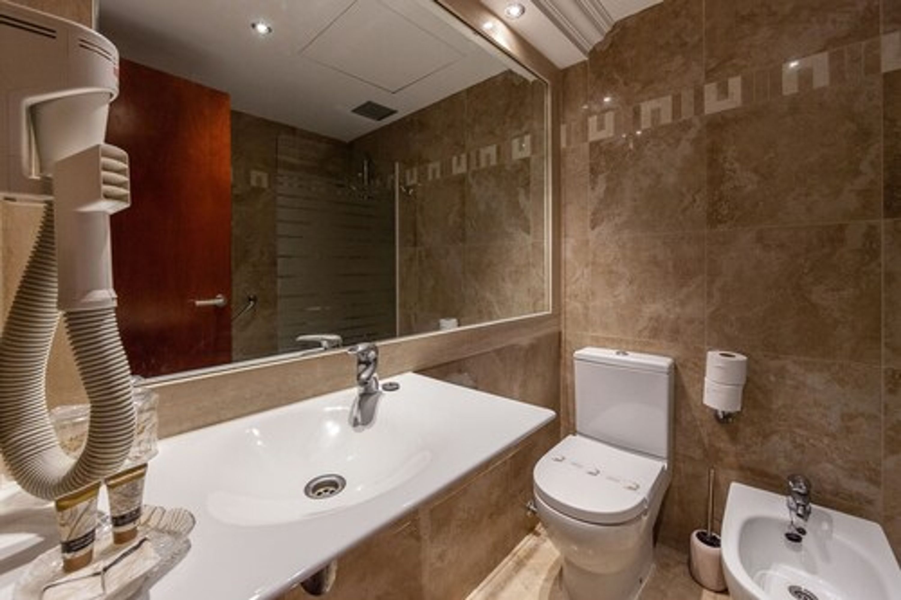 Une salle de bain moderne avec un grand lavabo, des toilettes, un bidet et un miroir.