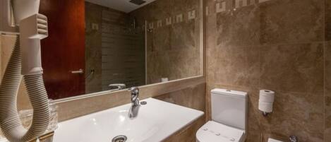 A modern bathroom with a large sink, toilet, bidet, and a mirror.