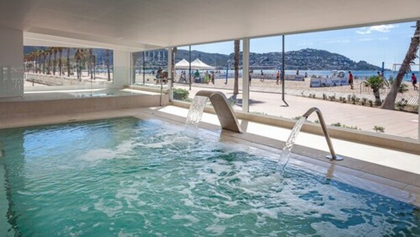 Una piscina interior con vistas despejadas a una playa y montañas.