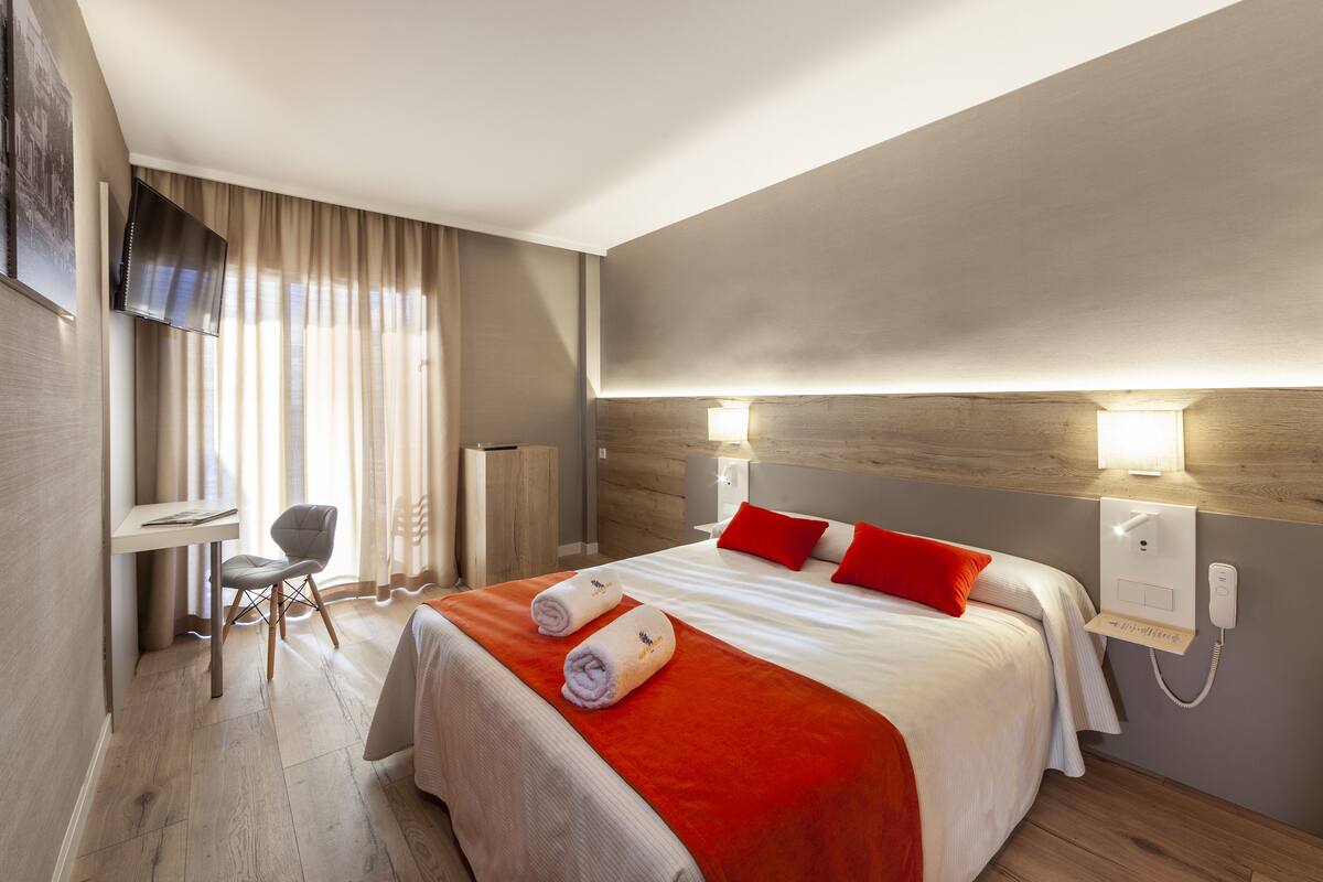 Ein Hotelzimmer mit Bett, Schreibtisch, Stuhl und Fernseher.