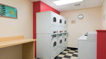 A laundry room with a large white washer and dryer, a clock on the wall, and a checkered floor.