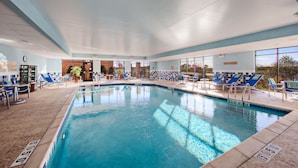 Una amplia piscina interior con sillones reclinables azules y un letrero que dice 'No Diving'.