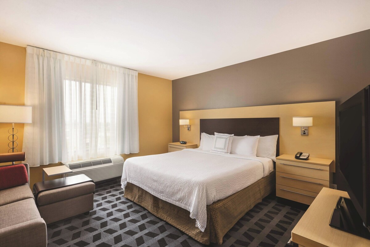 Une chambre d’hôtel avec un grand lit, des tables de chevet, un bureau, une chaise et un téléviseur.