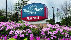Letrero de TownePlace Suites Marriott con un jardín de flores rosas al frente.