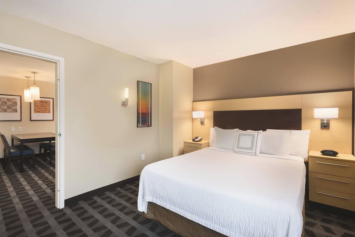 Habitación de hotel con una cama grande, mesitas de noche, un escritorio con sillas y una alfombra estampada.
