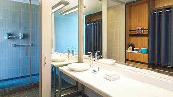 Un baño moderno con cabina de ducha de vidrio, lavamanos dobles y un espejo grande.