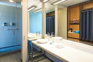 A modern bathroom with a glass shower enclosure, dual sinks, and a large mirror.