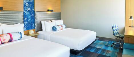 Una habitación de hotel con dos camas, un papel tapiz azul con diseño, una alfombra azul y una silla.
