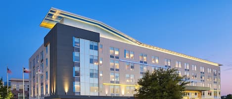 Ett modernt hotell med ett platt tak, stora fönster och en väl upplyst entré.