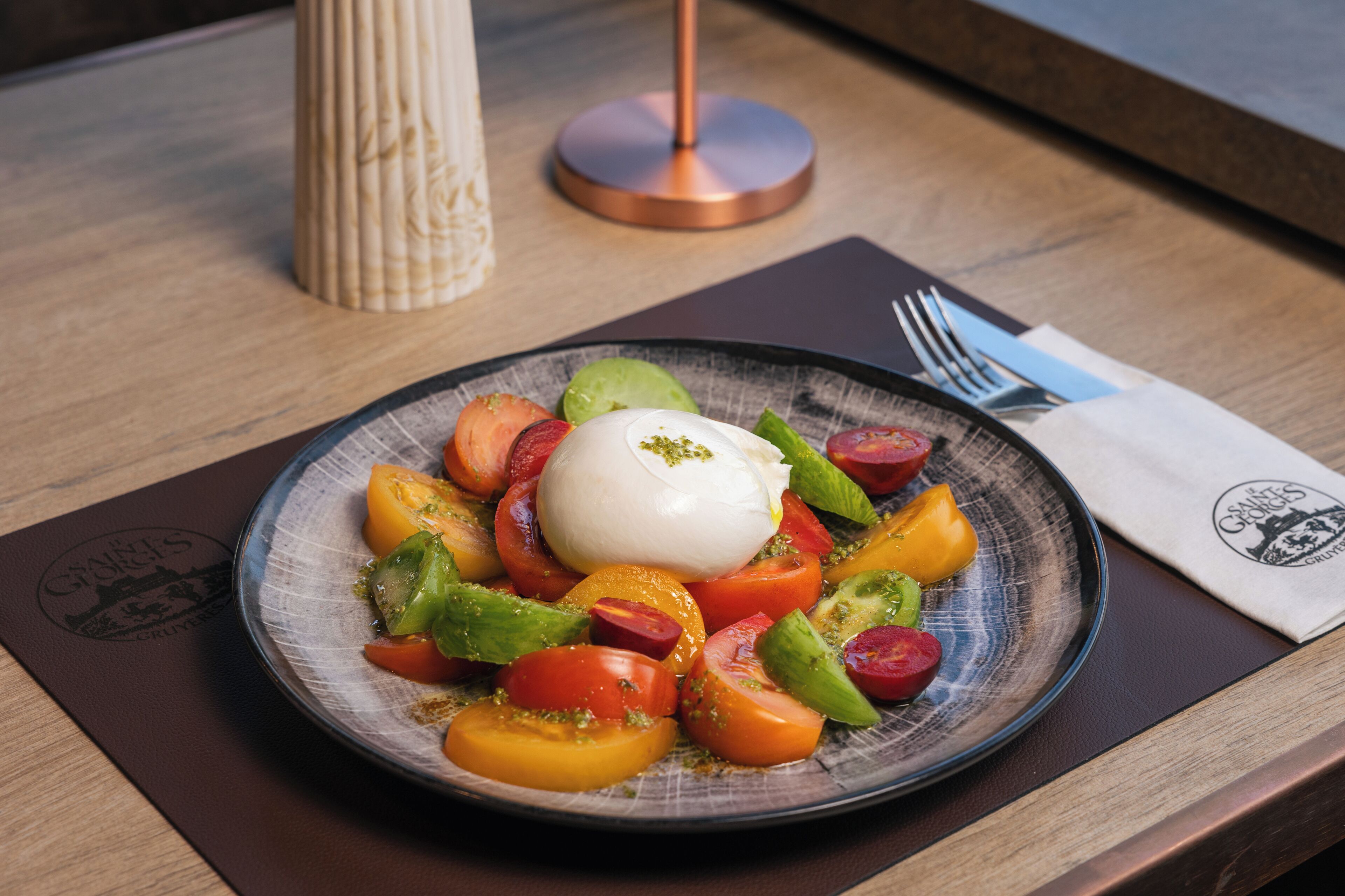 A plate of food with a poached egg and sliced tomatoes and peppers on a ceramic plate.