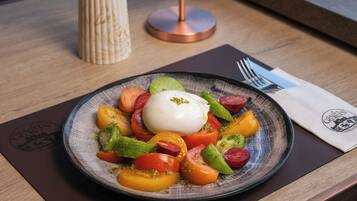 A plate of food with a poached egg and sliced tomatoes and peppers on a ceramic plate.