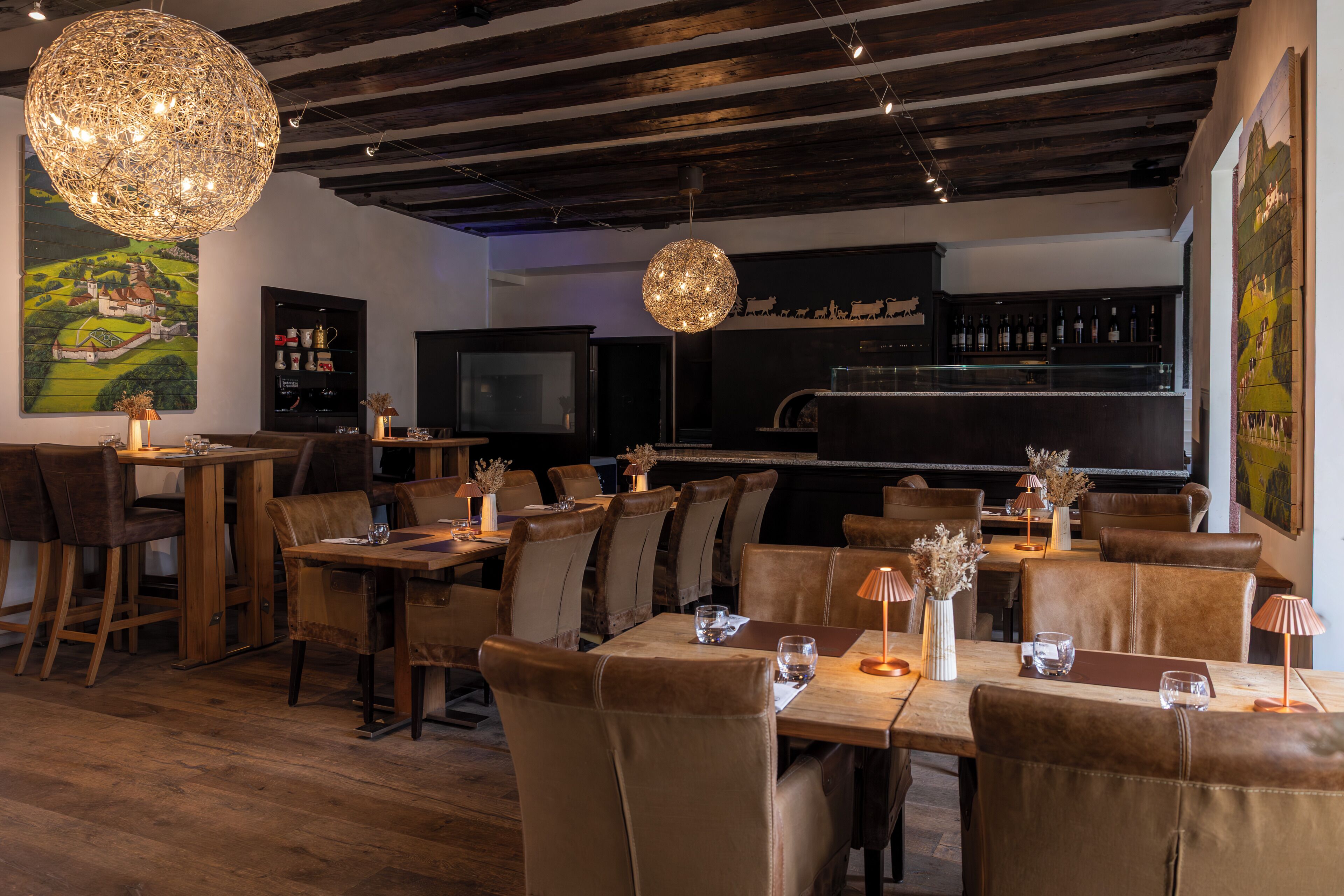 A restaurant with wooden tables and chairs, a bar area, and a large decorative light fixture.