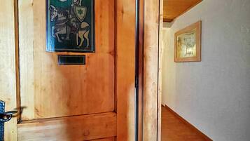 A wooden door with a decorative emblem, a metal handle, and a small window.