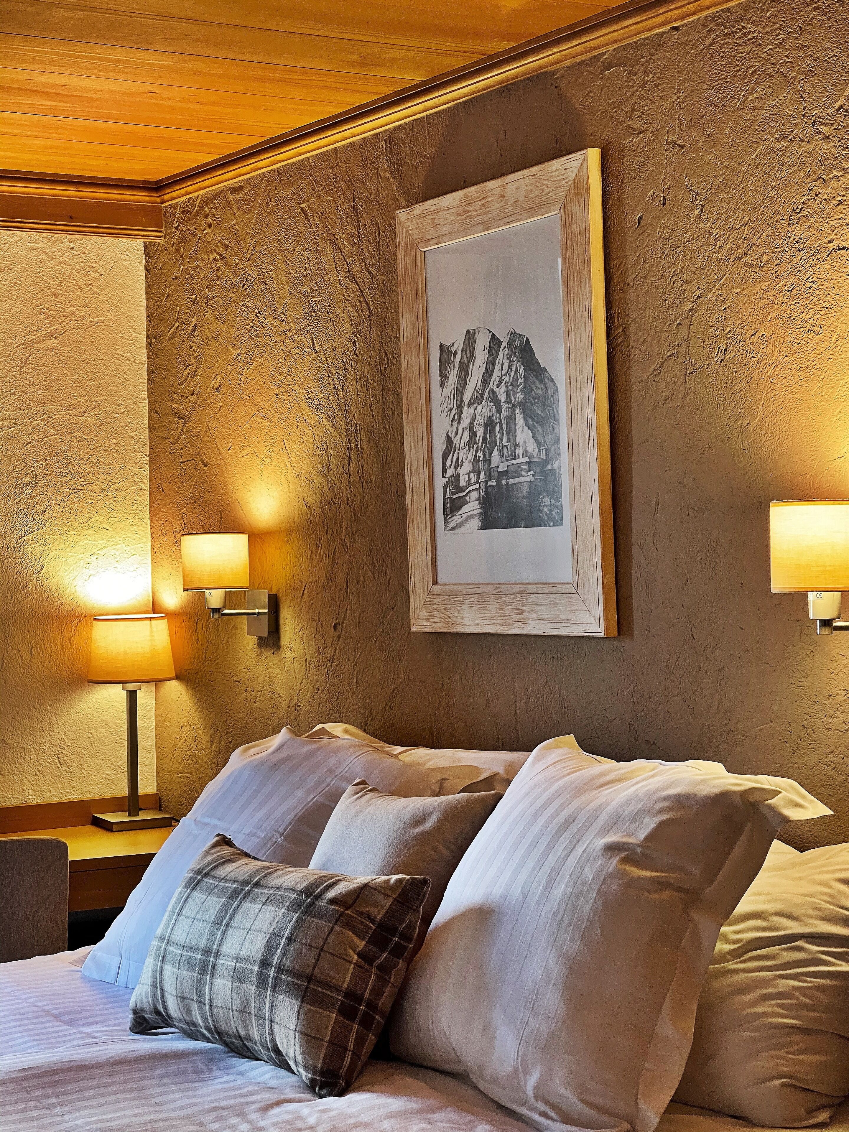 Habitación de hotel con cama, dos lámparas de pared y un cuadro en la pared.