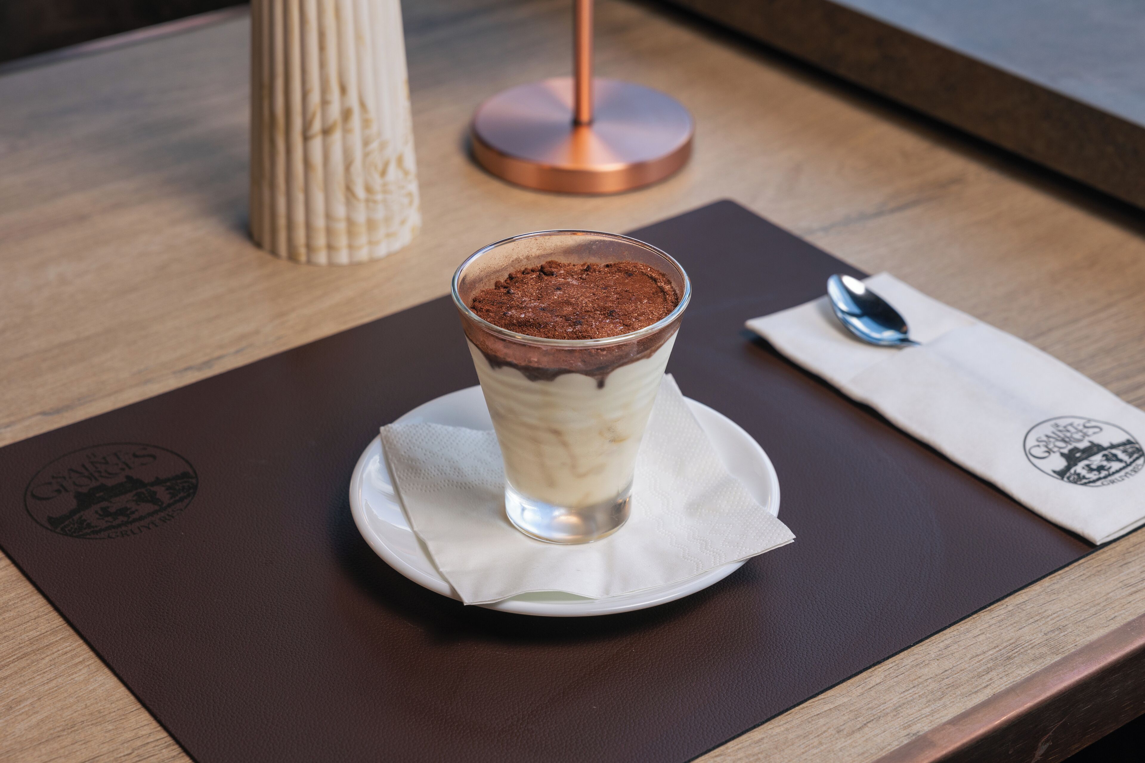 Un dessert servi dans un verre, posé sur une serviette en papier, sur une table en bois.